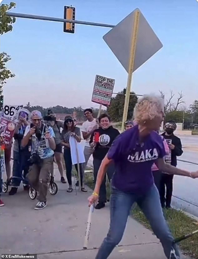 Protester wearing kindness shirt smashes piñata of Trump with pipe.
